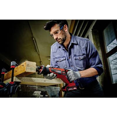 Mann mit Schutzbrille und Handschuhen schneidet Holz mit einer elektrischen Säge in einer Werkstatt.