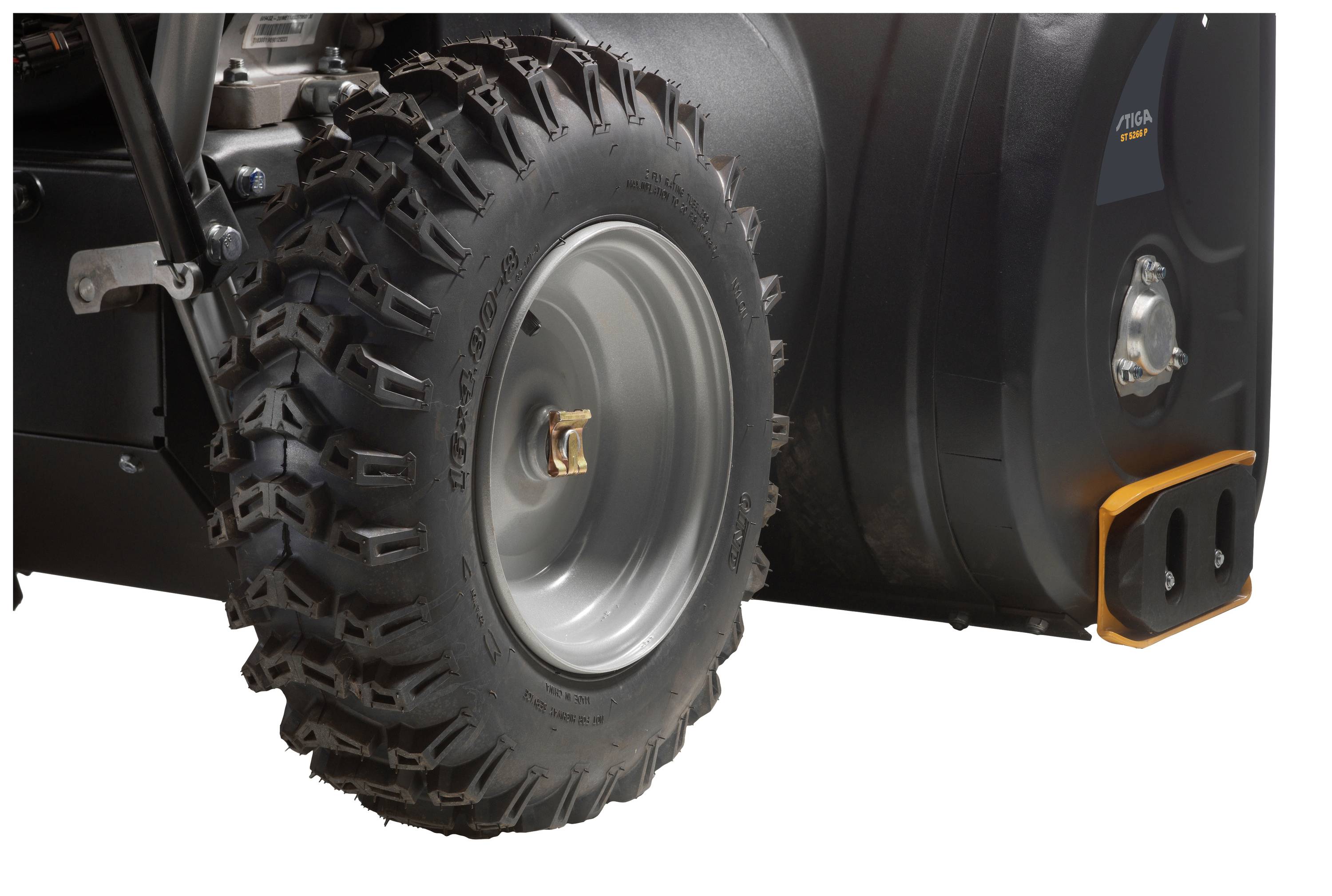 'Nahaufnahme eines robusten, grobstolligen Reifens an einem schwarzen Gerät oder Fahrzeug, das einen Teil des Rahmens und der Karosserie zeigt.'