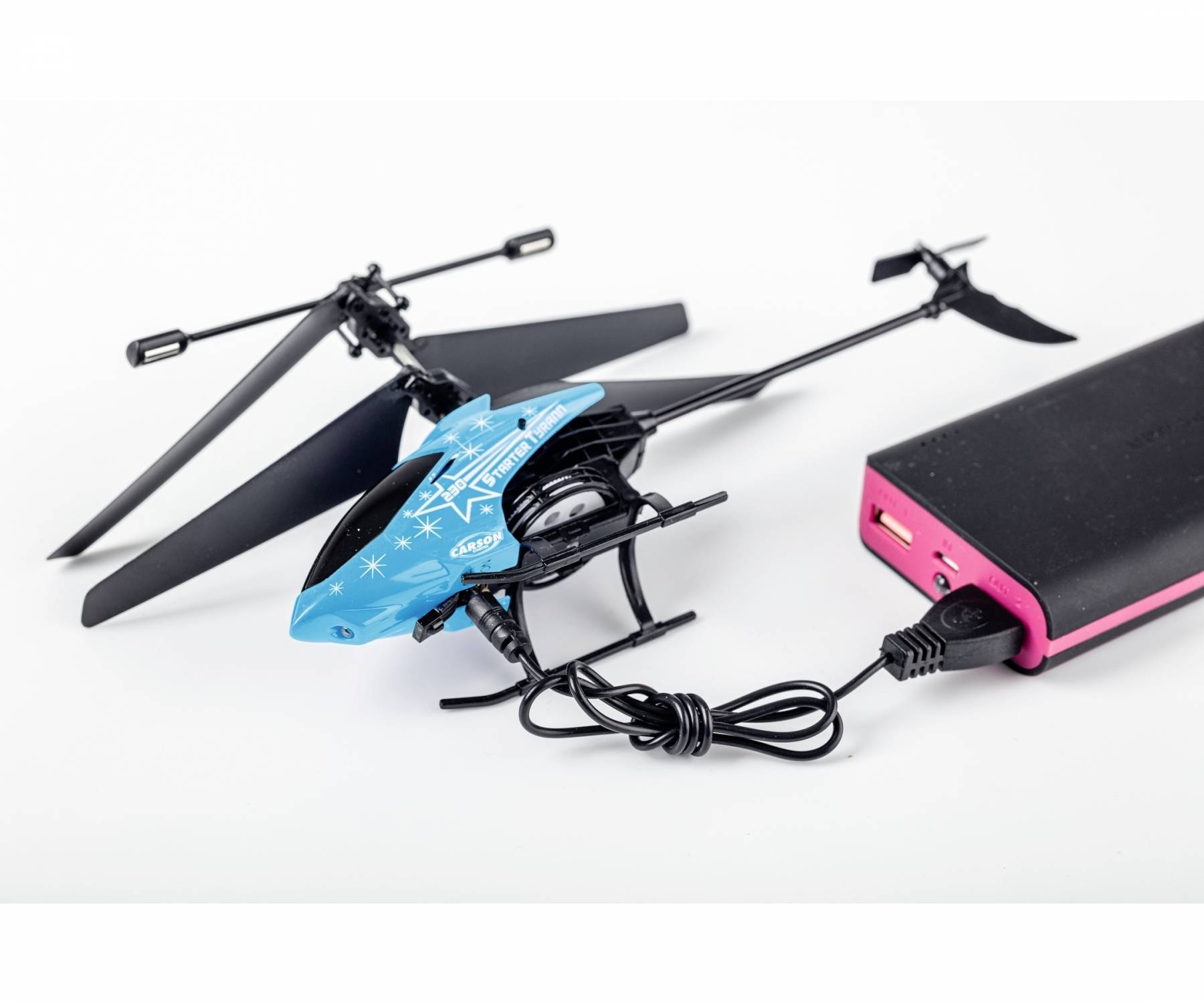 Ein kleines, blaues ferngesteuertes Hubschrauber-Modell ist mit einem rosa USB-Powerbank verbunden und wird aufgeladen.