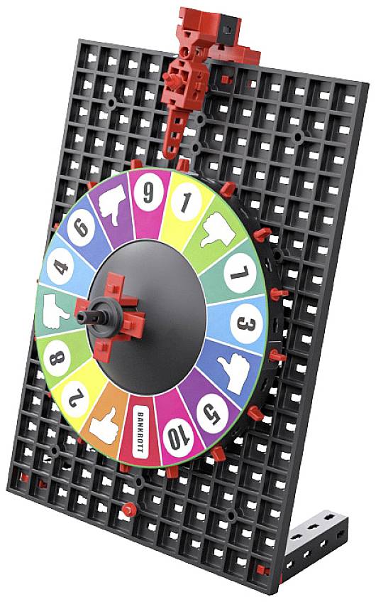 Buntes Glücksrad auf schwarzem Gitternetz, zeigt Zahlen und Daumenhochs/Runter-Symbole.