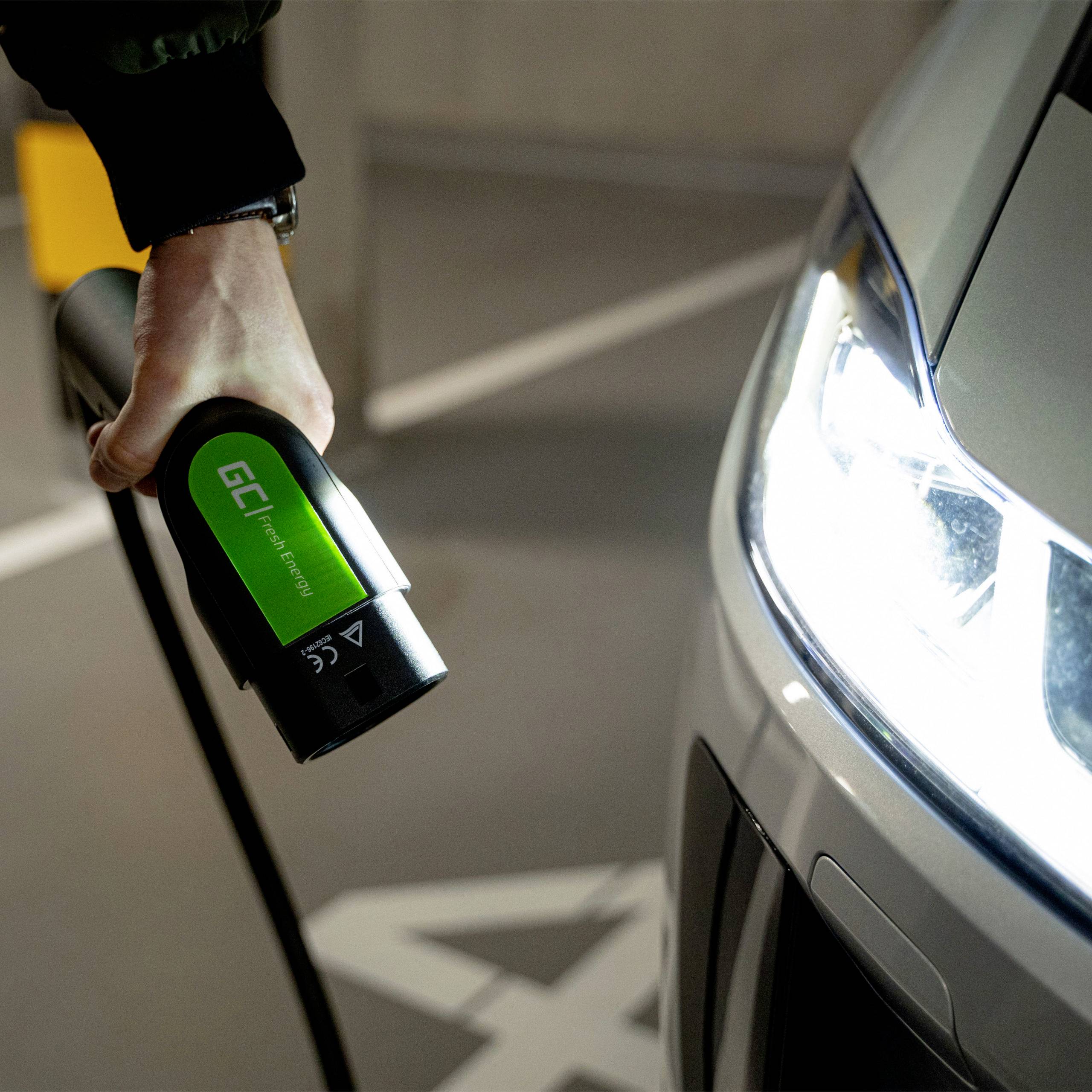 Eine Person lädt ein Elektroauto auf, indem sie ein Ladekabel mit einem grünen Etikett am Fahrzeug anschließt.