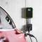 Ein rotes Elektroauto wird an einer Ladestation in einer Garage aufgeladen. Die Ladestation ist an der Wand montiert und zeigt den Ladezustand.