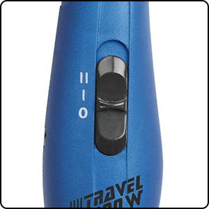 Ein blauer Haartrockner-Schalter, der zwischen zwei Einstellungen (II, I) und Aus (O) wechselt. 'Travel 2000W' ist darunter zu sehen.