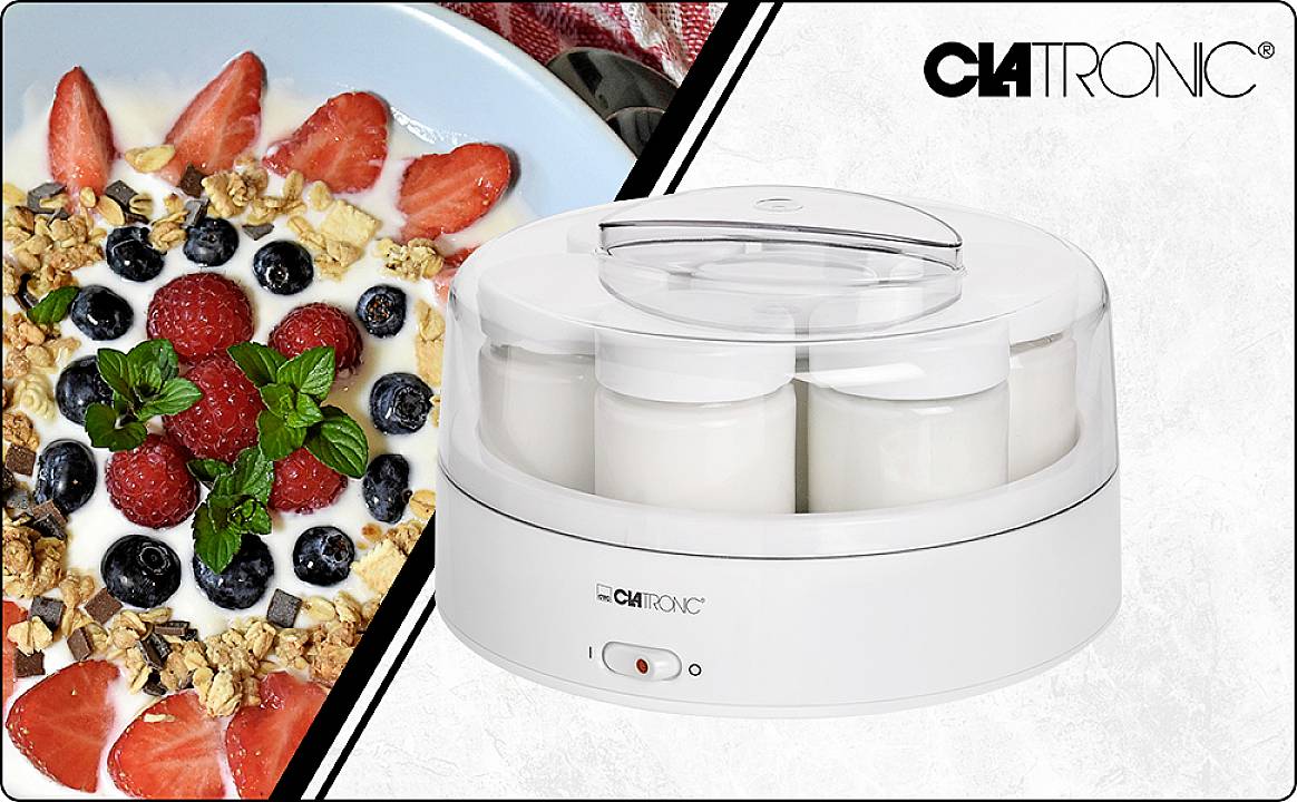 'Ein weißer Joghurtbereiter der Marke Clatronic mit vier Gläsern, daneben eine Schale mit Joghurt, frischen Beeren und Müsli.'