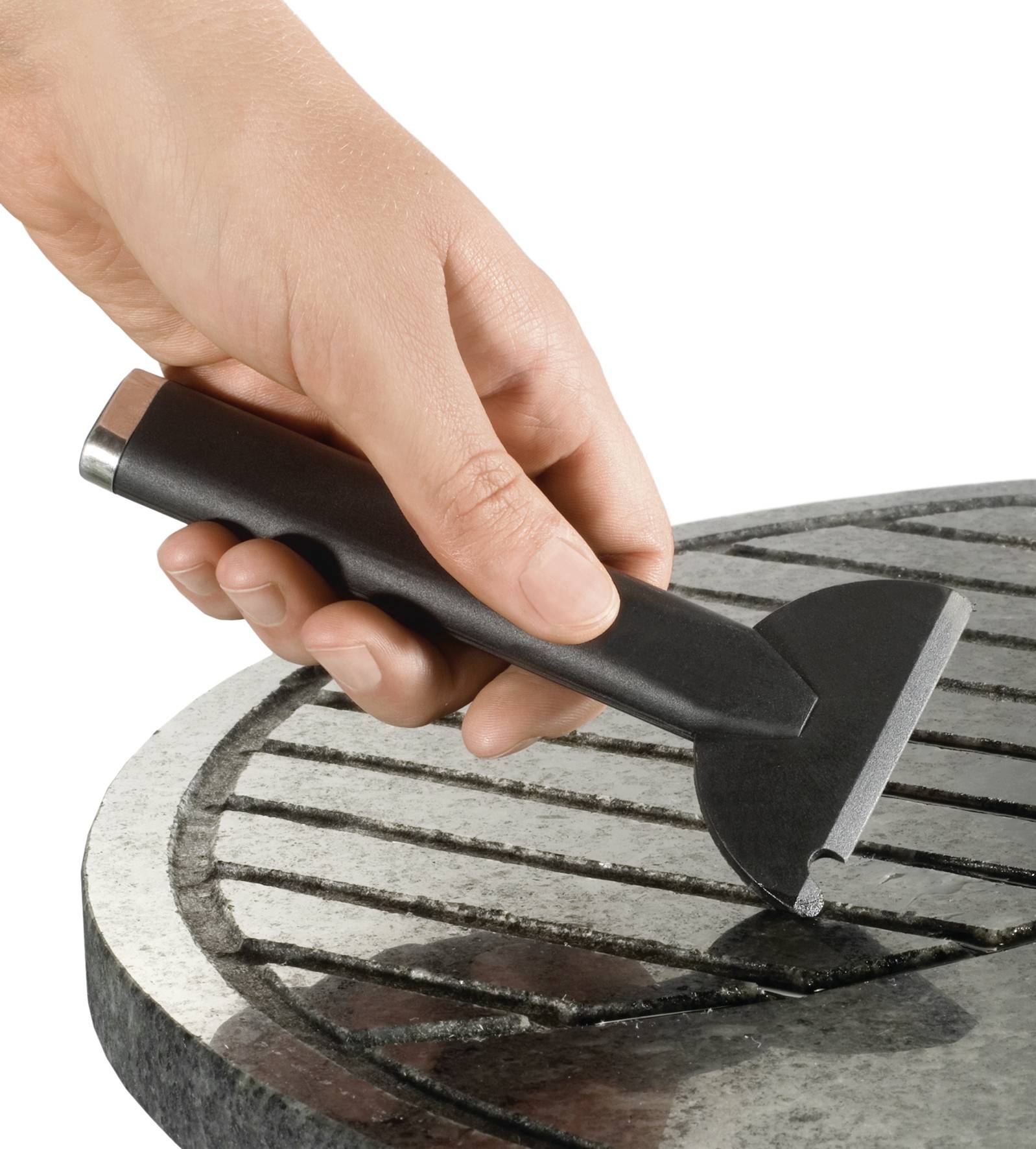 Eine Hand hält einen Grillrostschaber und reinigt ein gerilltes Metallgitter.