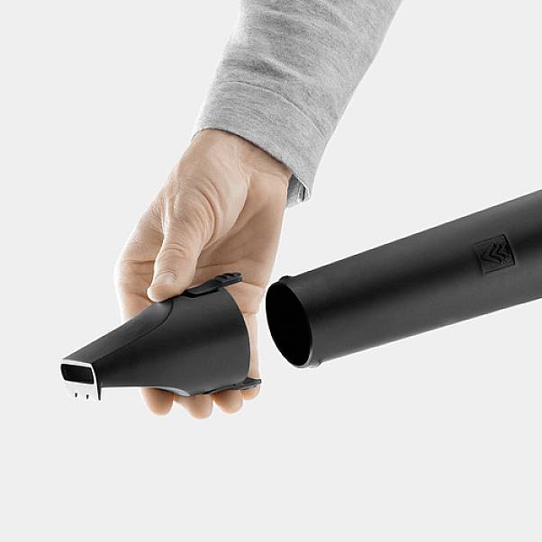 Eine Hand hält einen schwarzen, zylinderförmigen Staubsaugeraufsatz mit einem Düsenende, bereit zum Gebrauch in einem Staubsauger.