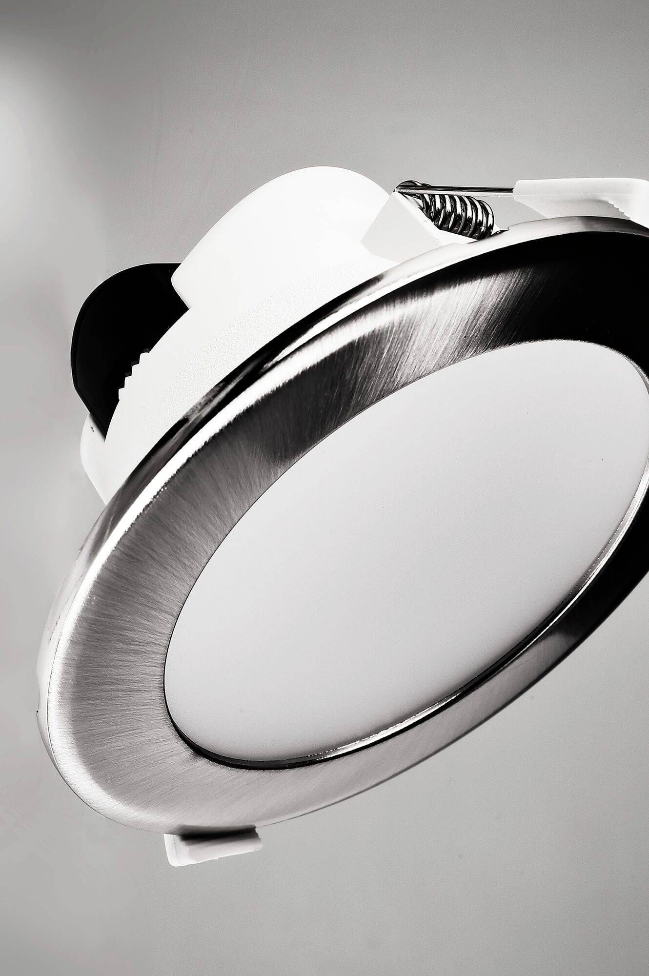 Runder LED-Deckeneinbaustrahler, silberner Rand, weißes Mittelteil, mit Federklemmen zur einfachen Montage.