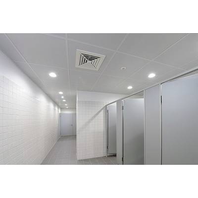 Ein steriler, moderner Toilettenraum mit weißen Fliesen, mehreren geschlossenen Kabinentüren und heller Deckenbeleuchtung.