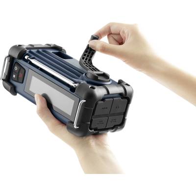 Eine Person hält ein tragbares blaues Gerät mit einem Griff, das wie ein Radio oder Lautsprecher aussieht.