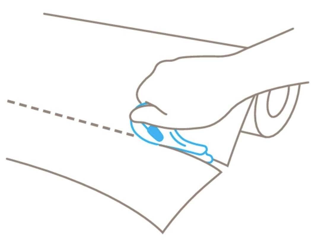 Eine Hand schneidet mit einem Cutter-Messer entlang einer gestrichelten Linie auf einem Blatt Papier.