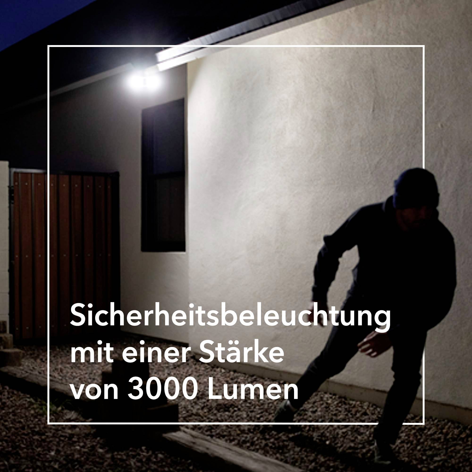 Eine Person bewegt sich nachts in einem beleuchteten Garten. Text: 'Sicherheitsbeleuchtung mit einer Stärke von 3000 Lumen'.