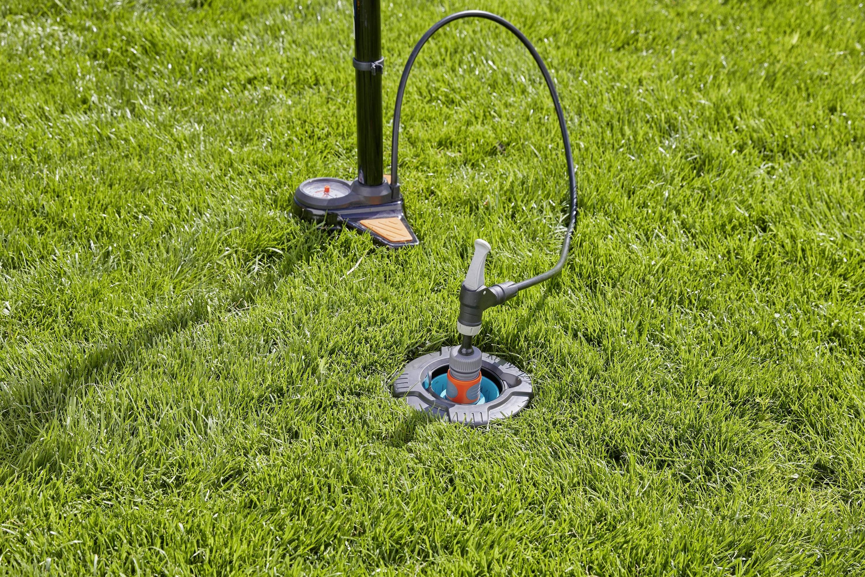 Ein auf einem Rasen installierter Rasensprenger wird von einem Druckventil auf einem Ständer gesteuert.