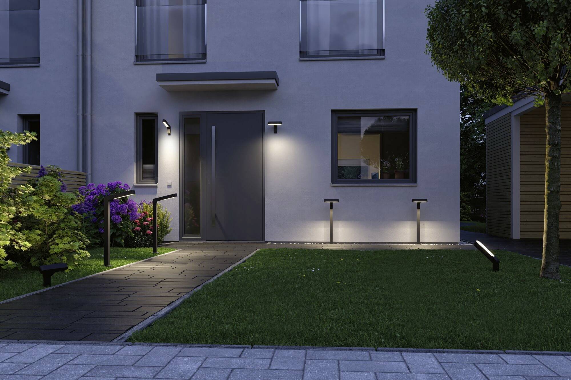 Abendaufnahme eines modernen Hauses mit beleuchtetem Eingangspfad und gepflegtem Garten. Die Außenbeleuchtung sorgt für einladende Atmosphäre.