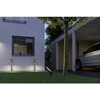 Ein Haus mit erleuchtetem Fenster und daneben ein Carport mit einem geparkten Auto. Im Vordergrund ist ein Baum und ein Rasen.