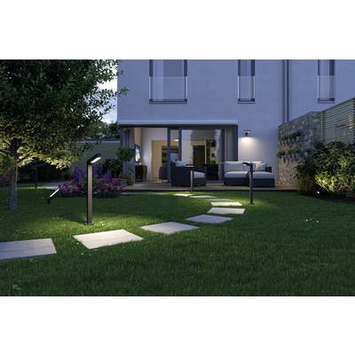 Ein Garten bei Nacht, beleuchtet durch Weglampen, führt zu einer Terrasse. Auf der Terrasse sind Sofas und ein Tisch vor einem modernen Haus.