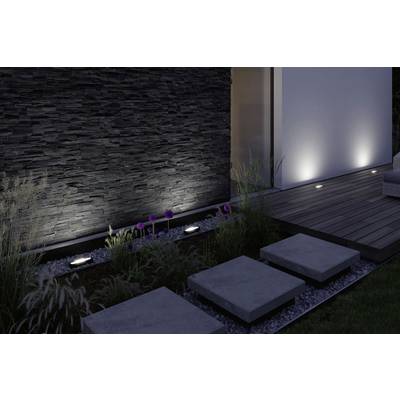 Moderner Garten mit beleuchteten Steinplatten und einer beleuchteten Steinwand. Gräser und Blumen säumen den Gehweg.