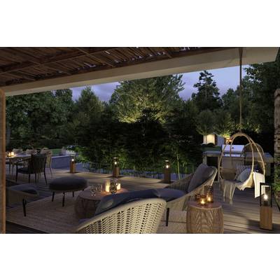 Eine gemütliche Terrasse bei Dämmerung, ausgestattet mit Rattanmöbeln und Kerzenlicht, umgeben von Bäumen und einem leuchtenden Garten.