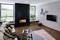 Modernes Wohnzimmer mit Kamin, bequemer Couch und großem Fenster. Holzfußboden, Fernseher an der Wand, beruhigende Atmosphäre.