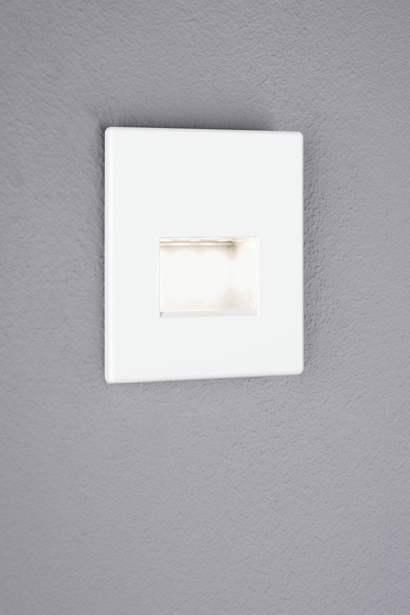 Ein quadratisches, weißes Wandleuchten auf einer grauen Wand, das diffuses Licht nach unten abstrahlt. Geeignet für Treppenbeleuchtung.