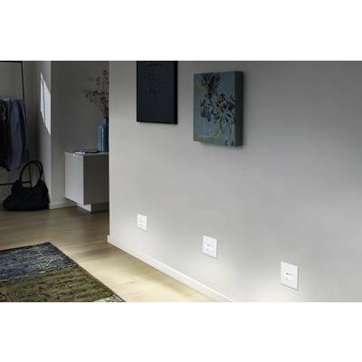 Ein heller Flur mit Holzboden, Teppich und zwei an der Wand hängenden Kunstwerken. Links steht ein kleiner Tisch mit Vasen.