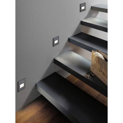 Treppe mit moderner Beleuchtung; rechts eine Tasche mit Schlüssel und Brille auf einer Stufe. Dunkle Stufen kontrastieren mit heller Wand.