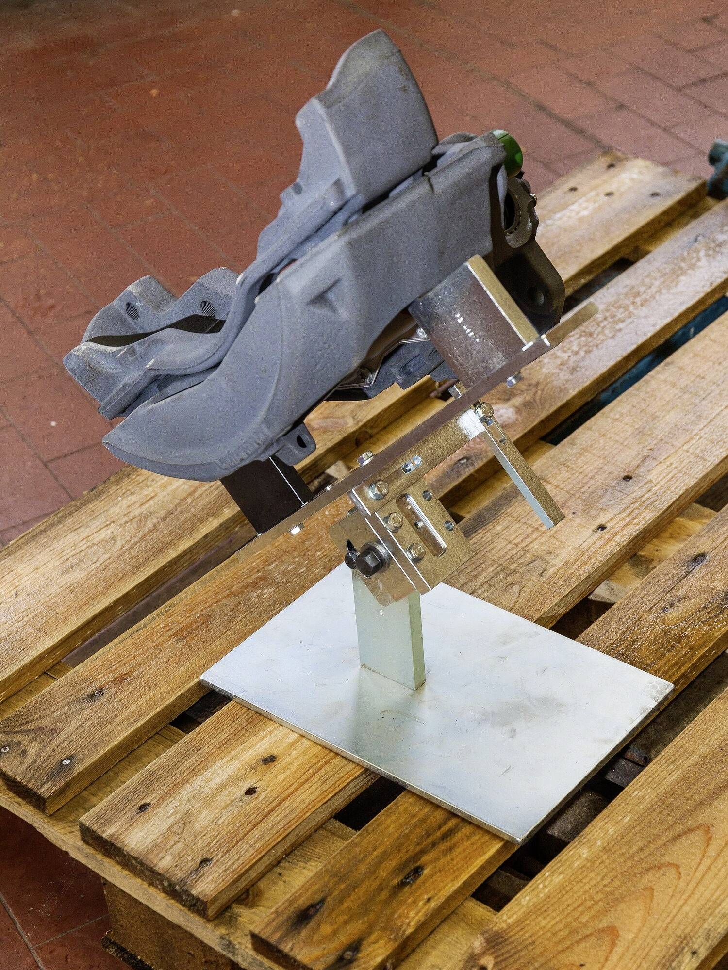 Eine Metallkonstruktion und ein Steinbrecher-Modell sind auf einem Holzpalettensockel montiert. Sie stehen auf einem Ziegelboden.