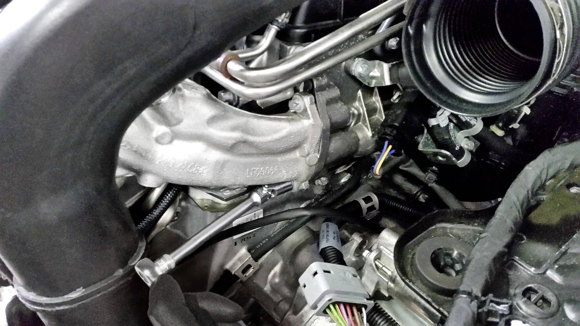 Ein detailliertes Foto eines Autoturbos, das komplexe Teile wie Rohre und Kabel zeigt, die den Motorbereich eines Fahrzeugs darstellen.