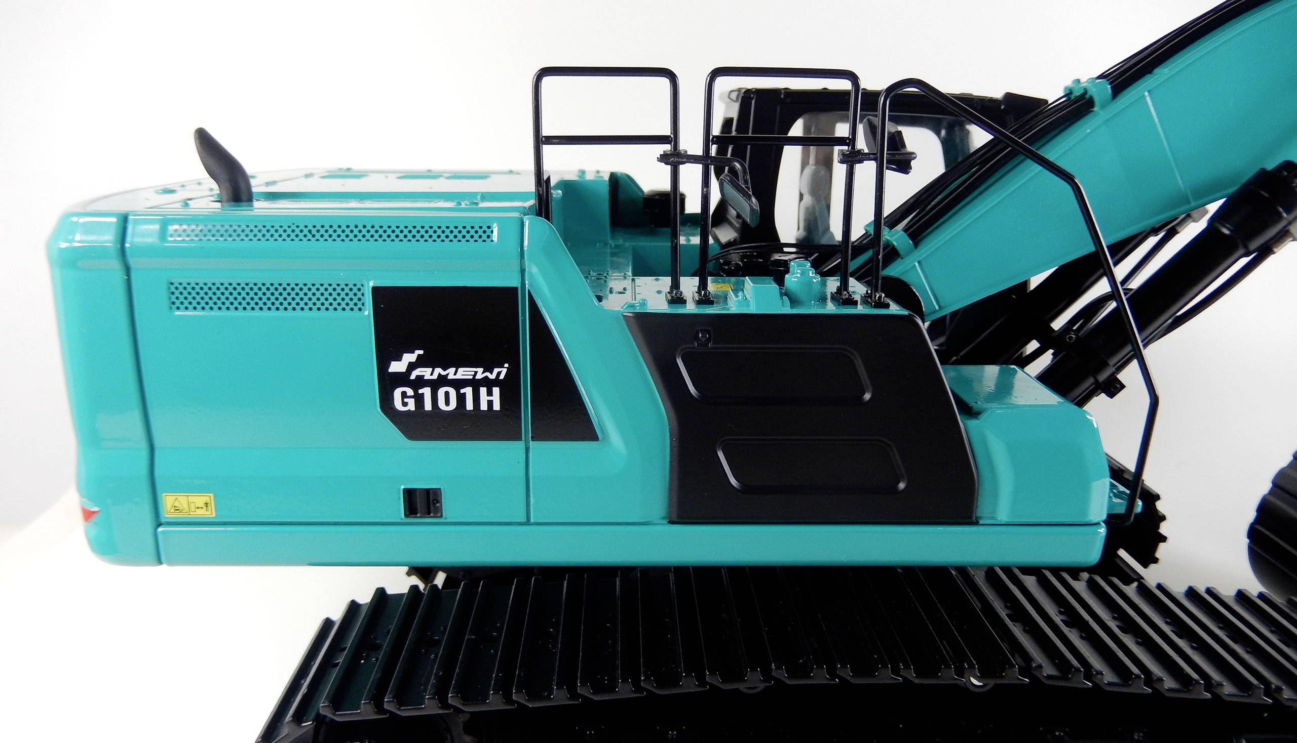 Bagger in türkiser Farbe von der Seite, mit Aufschrift 'G101H'. Die Ketten und ein Teil des Auslegers sind sichtbar.