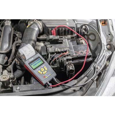 Elektronisches Diagnosegerät misst Autobatteriespannung im geöffneten Motorraum. Rotes und schwarzes Kabel sind angeschlossen.