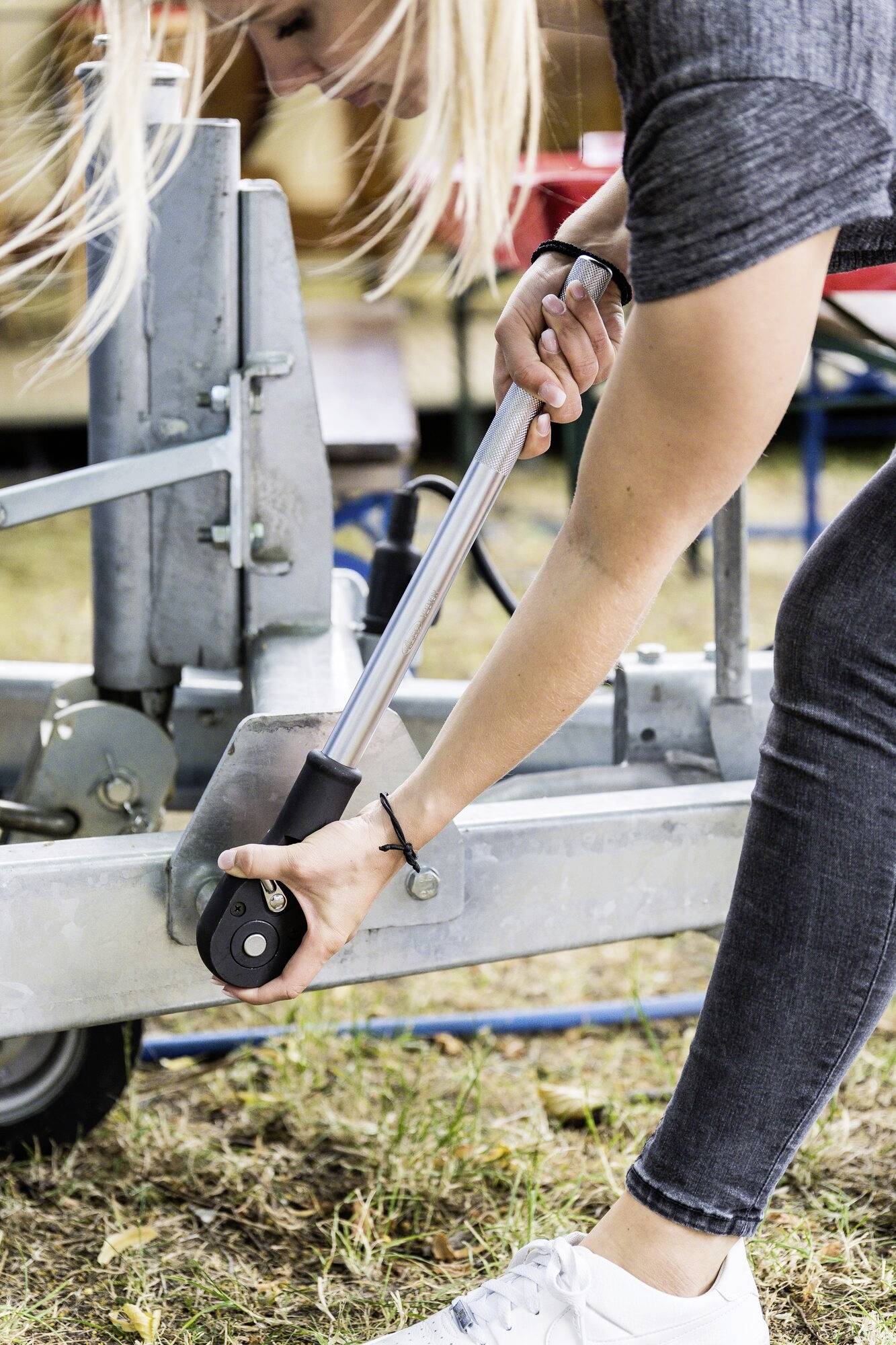 Person zieht mechanischen Hebel an einem metallischen Gerät im Freien.