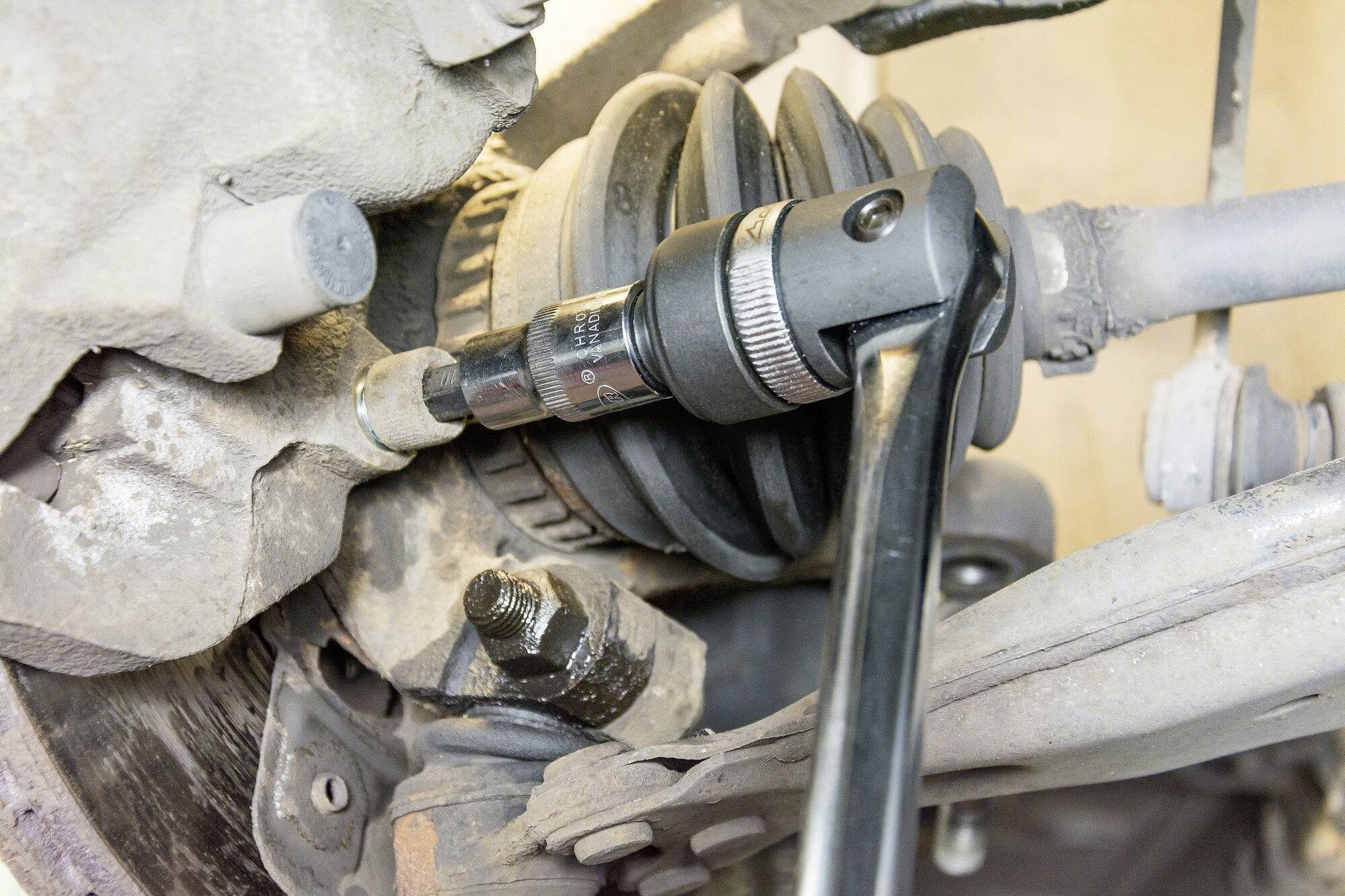 Mechanikerwerkzeug bei der Arbeit an einem Autoteil, zeigt eine Nahaufnahme einer Ratsche, die eine Schraube an einem Fahrwerksystem dreht.