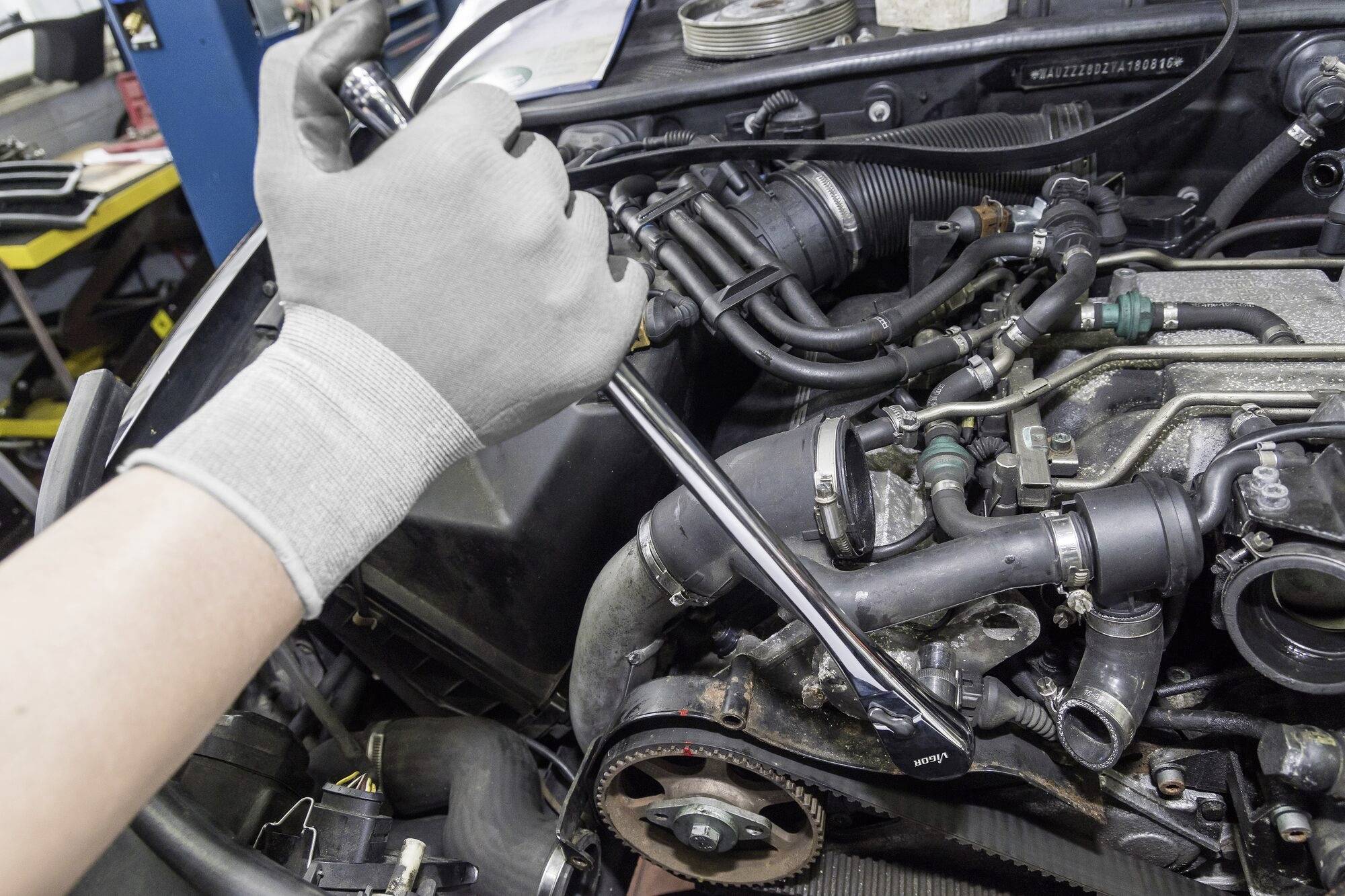 'Eine Person repariert einen Automotor mit einem Schraubenschlüssel.'