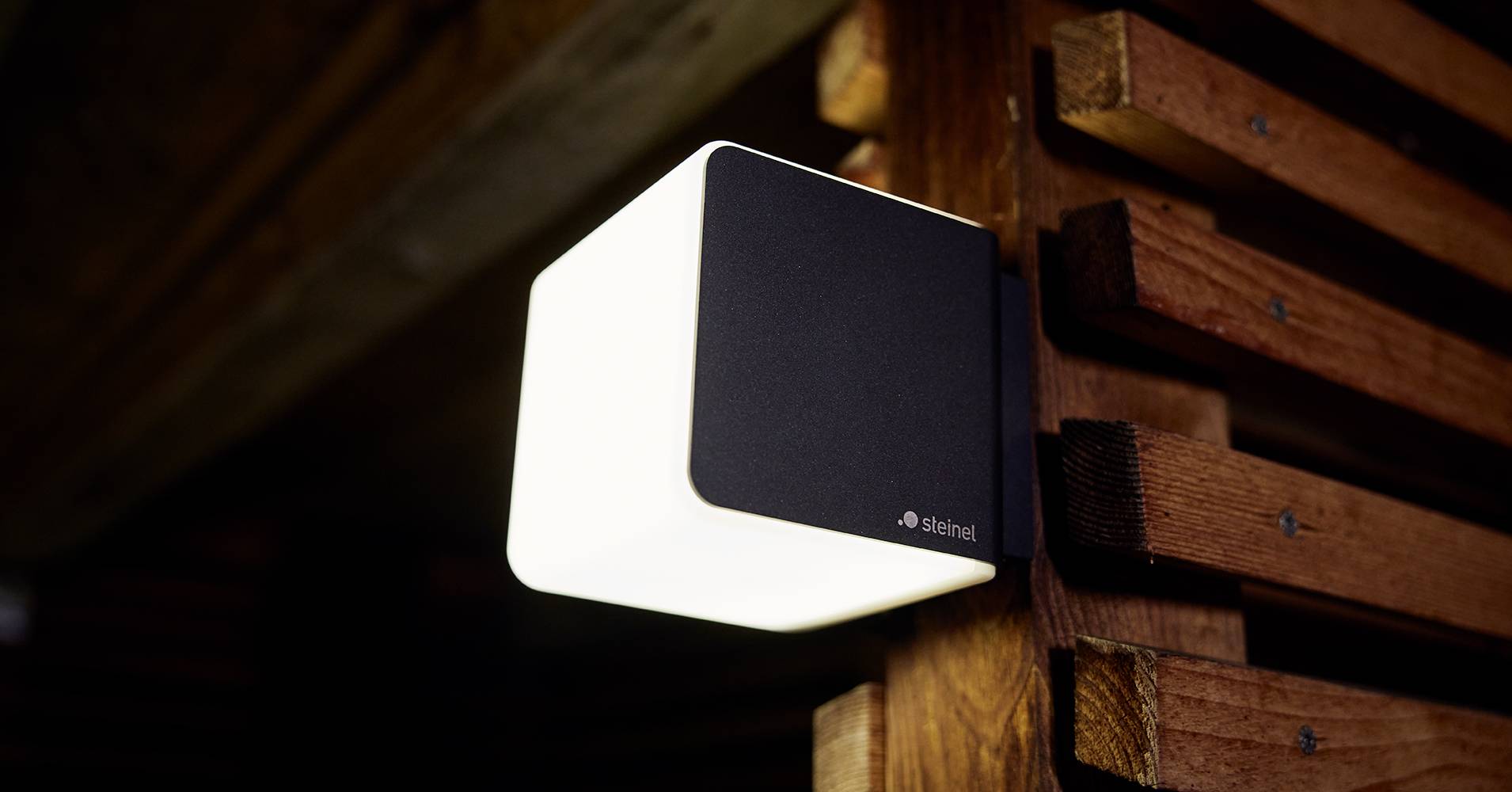 Außenleuchte in modernem Design leuchtet hell an einer Holzwand, sorgt für Beleuchtung und Akzentuierung der Umgebung.