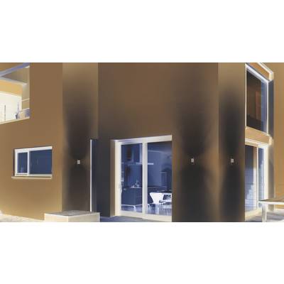 Ein modernes Haus bei Nacht mit großen Fenstern, die einen hell erleuchteten Innenraum zeigen. Die Fassade ist schlicht und geometrisch.