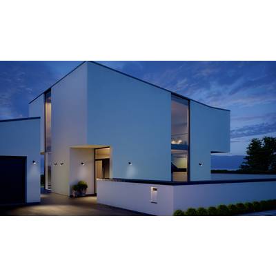 Modernes zweistöckiges Haus mit klaren Linien und großen Glasfenstern bei Sonnenuntergang, umgeben von minimalistischen Pflanzen.