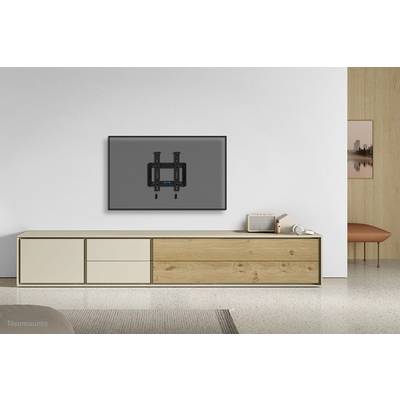 Ein moderner Wohnraum mit einem niedrigen Holz-Sideboard. An der Wand hängt ein großer, dunkler Fernseher.