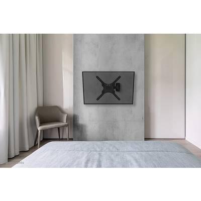 Ein modernes Schlafzimmer zeigt einen an der Wand montierten Flachbildfernseher, einen Stuhl und ein Bett mit blauer Bettdecke.