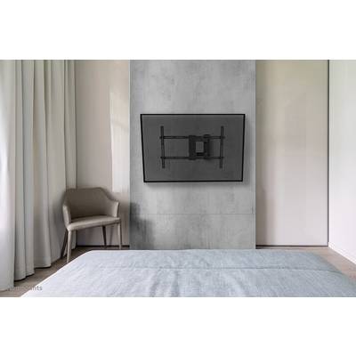 'Schlafzimmer mit grauer Wand, Fernseher an der Wandhalterung, ein Stuhl links neben einem Fenster, Bett im Vordergrund.'