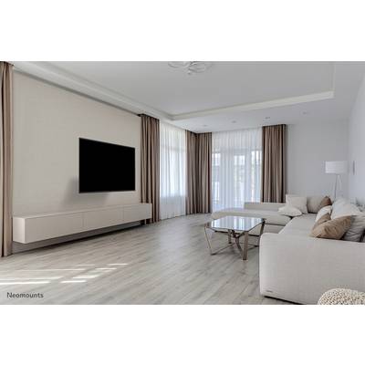 Helles Wohnzimmer mit modernem Sofa, Glastisch und großem Flachbildfernseher an der Wand. Große Fenster mit langen Vorhängen.