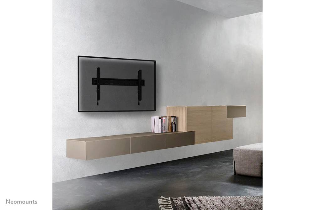Ein modernes Wohnzimmer mit einer Wandhalterung für einen Fernseher, schwebendes Sideboard mit Büchern, minimalistische Einrichtung.