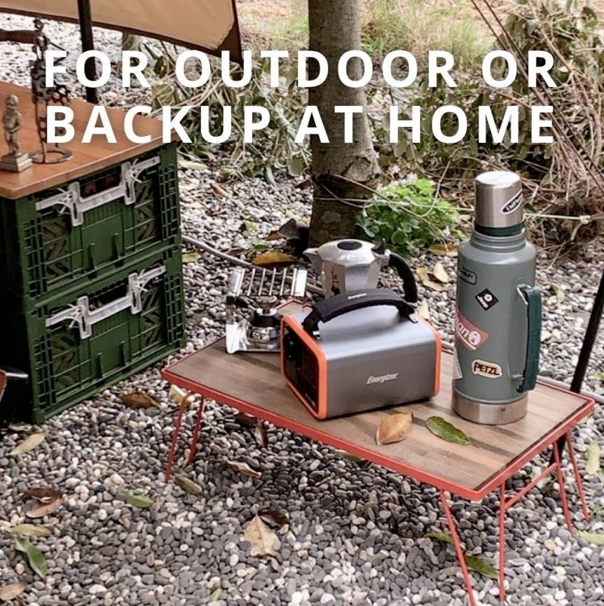 Campingausrüstung im Freien aufgestellt: Tisch mit tragbarem Generator, Thermoskanne und Campingkocher. Text: 'For outdoor or backup at home'.