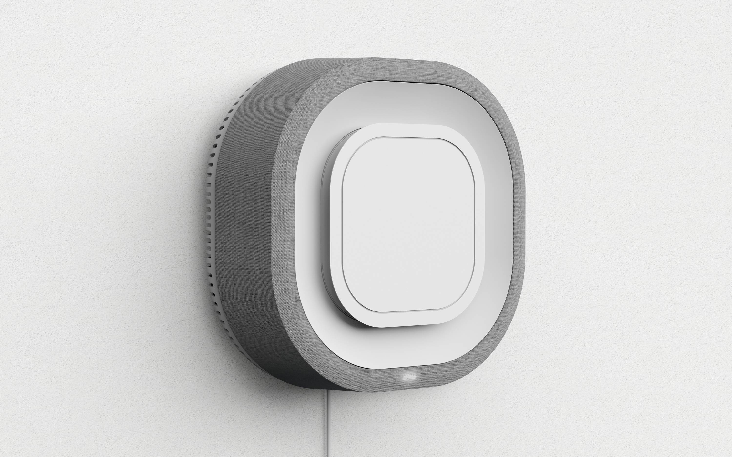 Ein quadratisches, modernes Thermostat mit abgerundeten Ecken an der Wand. Es hat einen grauen Rahmen und ein zentrales Display.