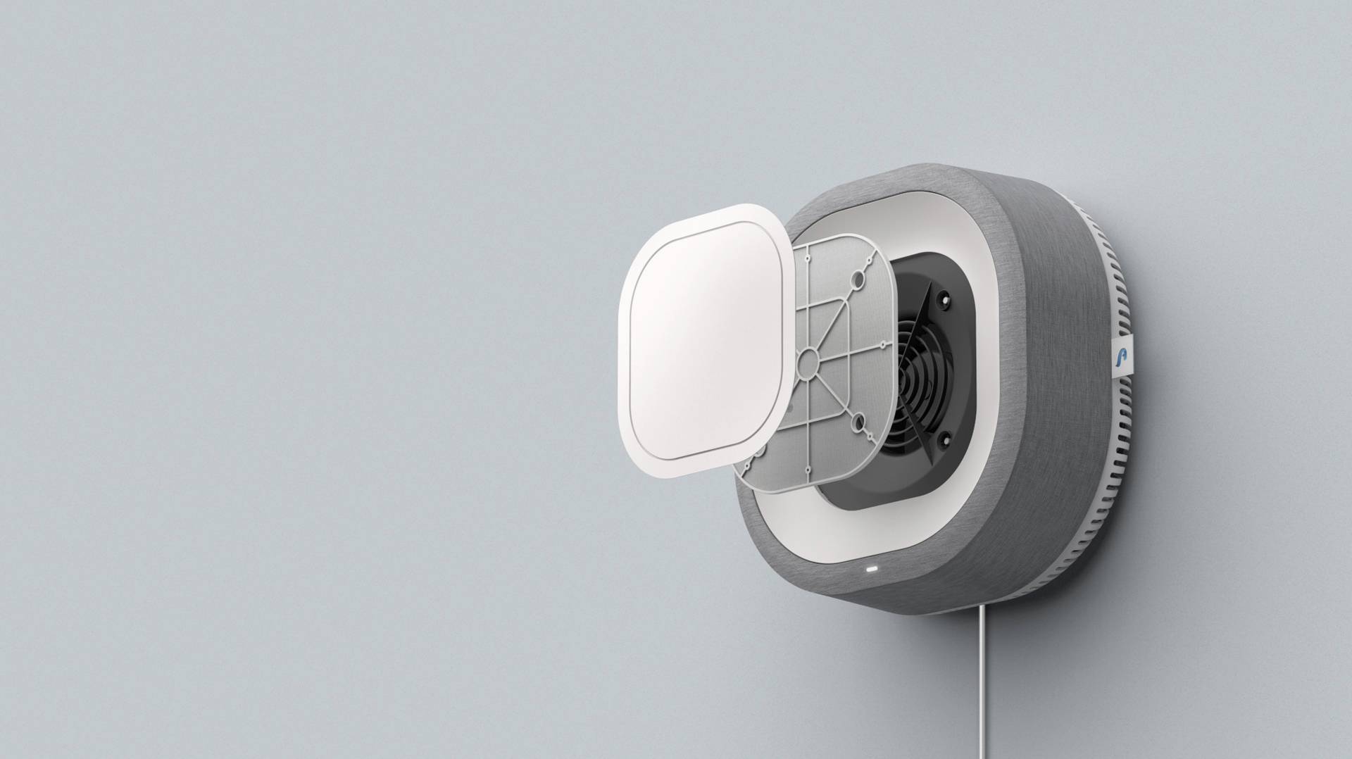 Ein smarter Luftfilter mit rundem Gehäuse an einer grauen Wand, geöffnet, um den inneren Ventilator und den abnehmbaren Filter zu zeigen.