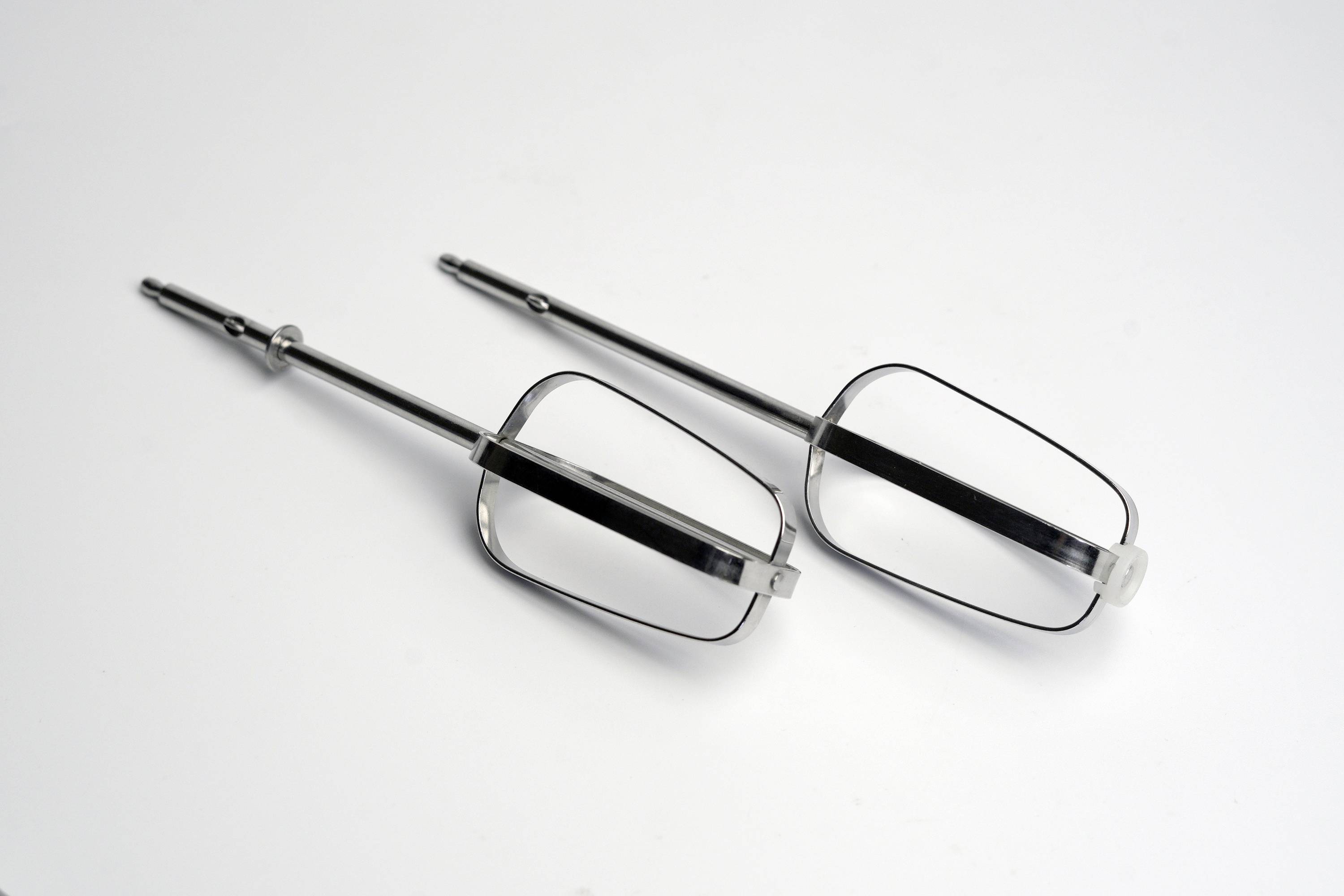 Zwei Metallrührbesen auf einer weißen Oberfläche.