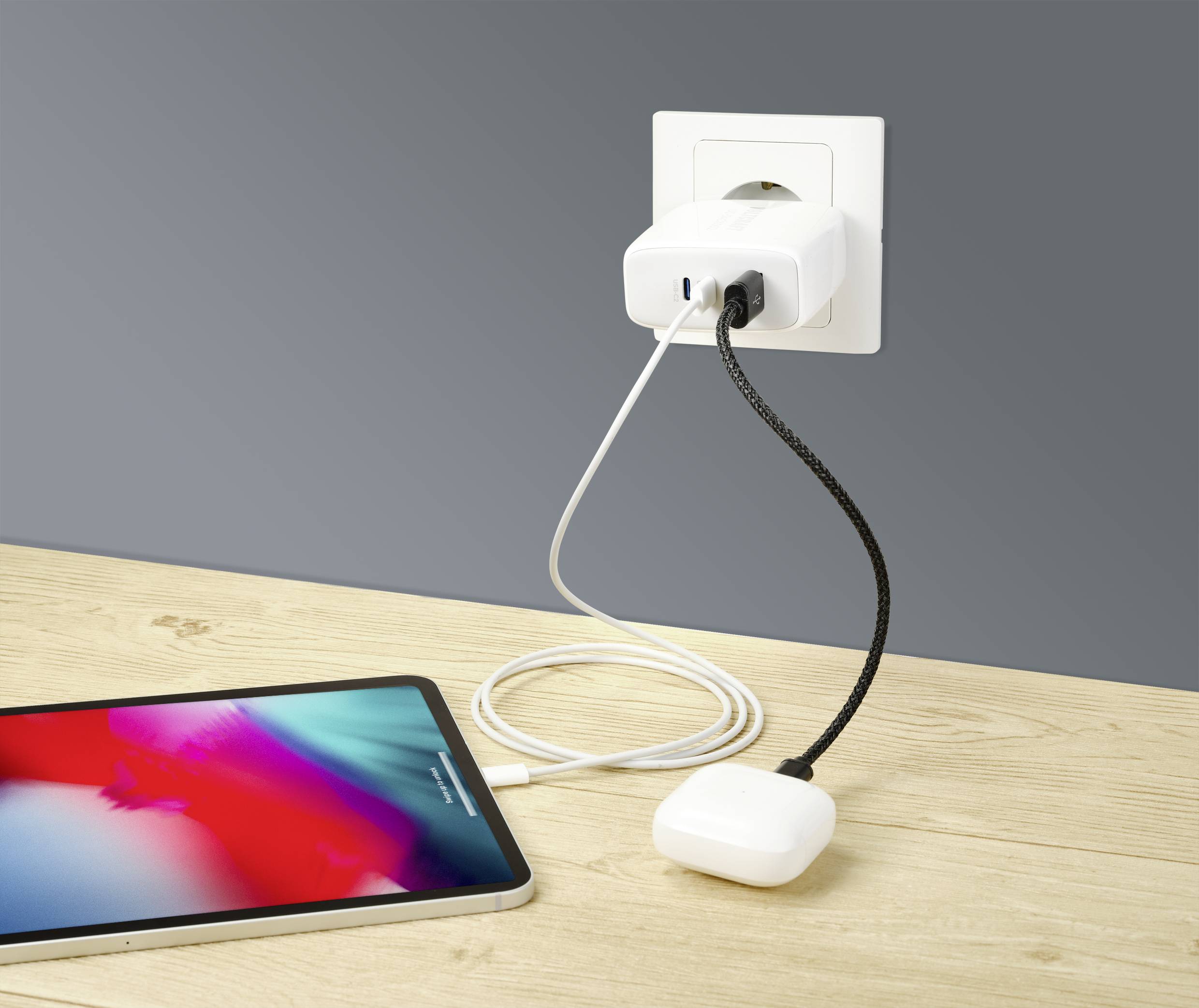 Ein Smartphone wird mit einem Ladegerät über ein USB-Kabel an eine Steckdose angeschlossen, während es auf einem Holztisch liegt.