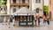 Ein kleiner, achteckiger Kiosk auf einem Stadtplatz mit Menschen, die vorbeigehen und stehen. Gebäude im Hintergrund.