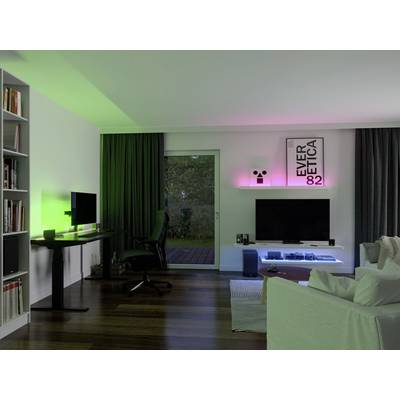 Modernes Wohnzimmer mit Schreibtisch, Computer, Fernseher und stimmungsvoller Beleuchtung in Grün und Rosa. Große Fensterfront mit Ausblick.