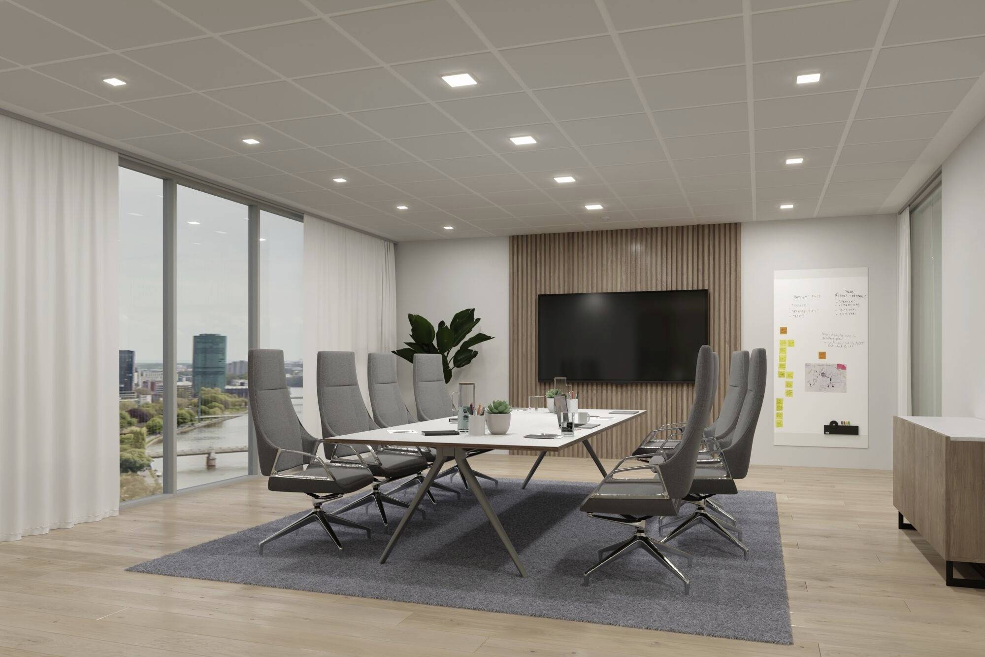 Moderner Konferenzraum mit großem Tisch, umgeben von grauen Stühlen. Fenster zeigen Stadtansicht. Tafel und Monitor an der Wand für Präsentationen.