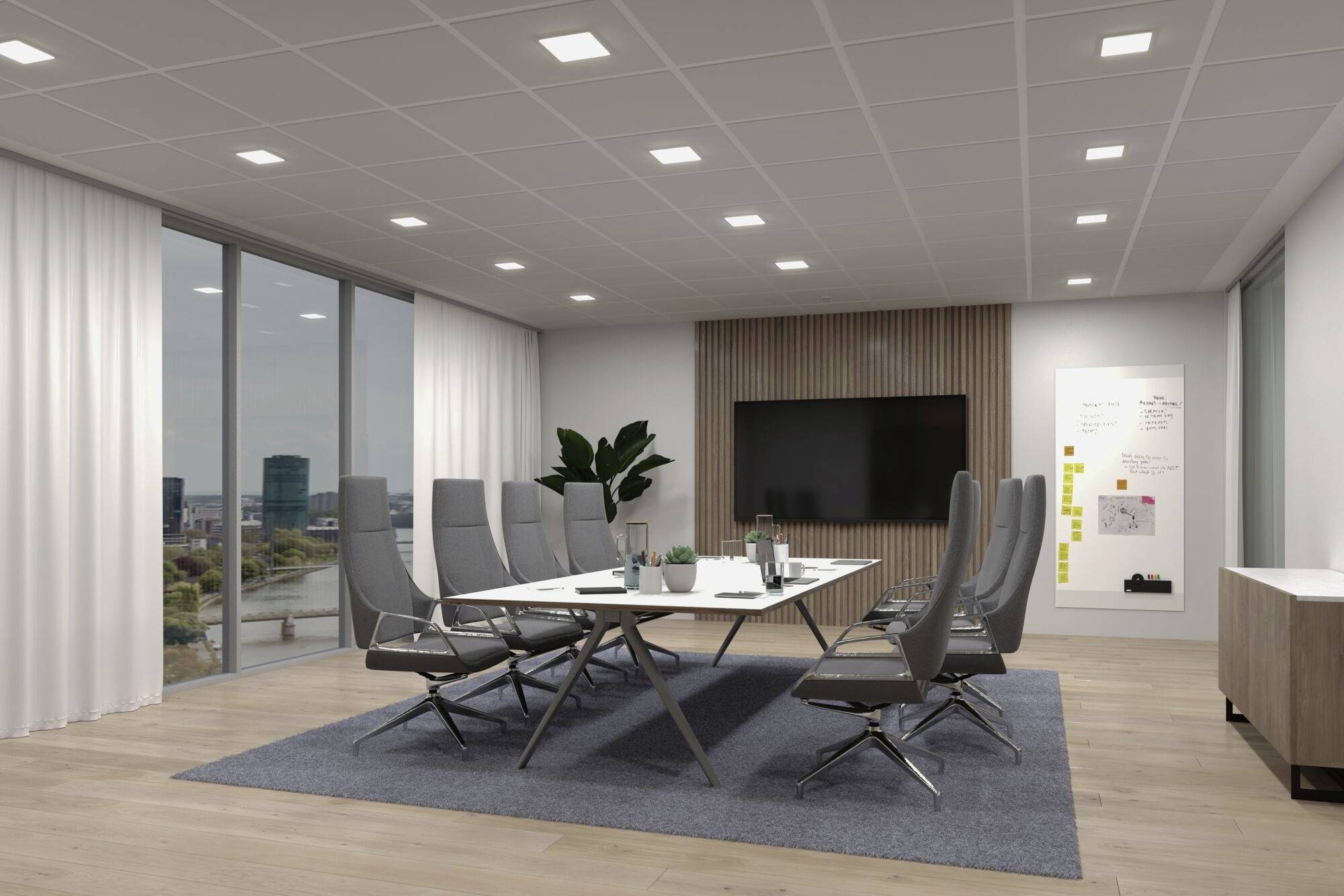 Konferenzraum mit großem Tisch, acht Stühlen, Whiteboard und Monitor. Große Fenster bieten Blick auf die Stadtlandschaft.