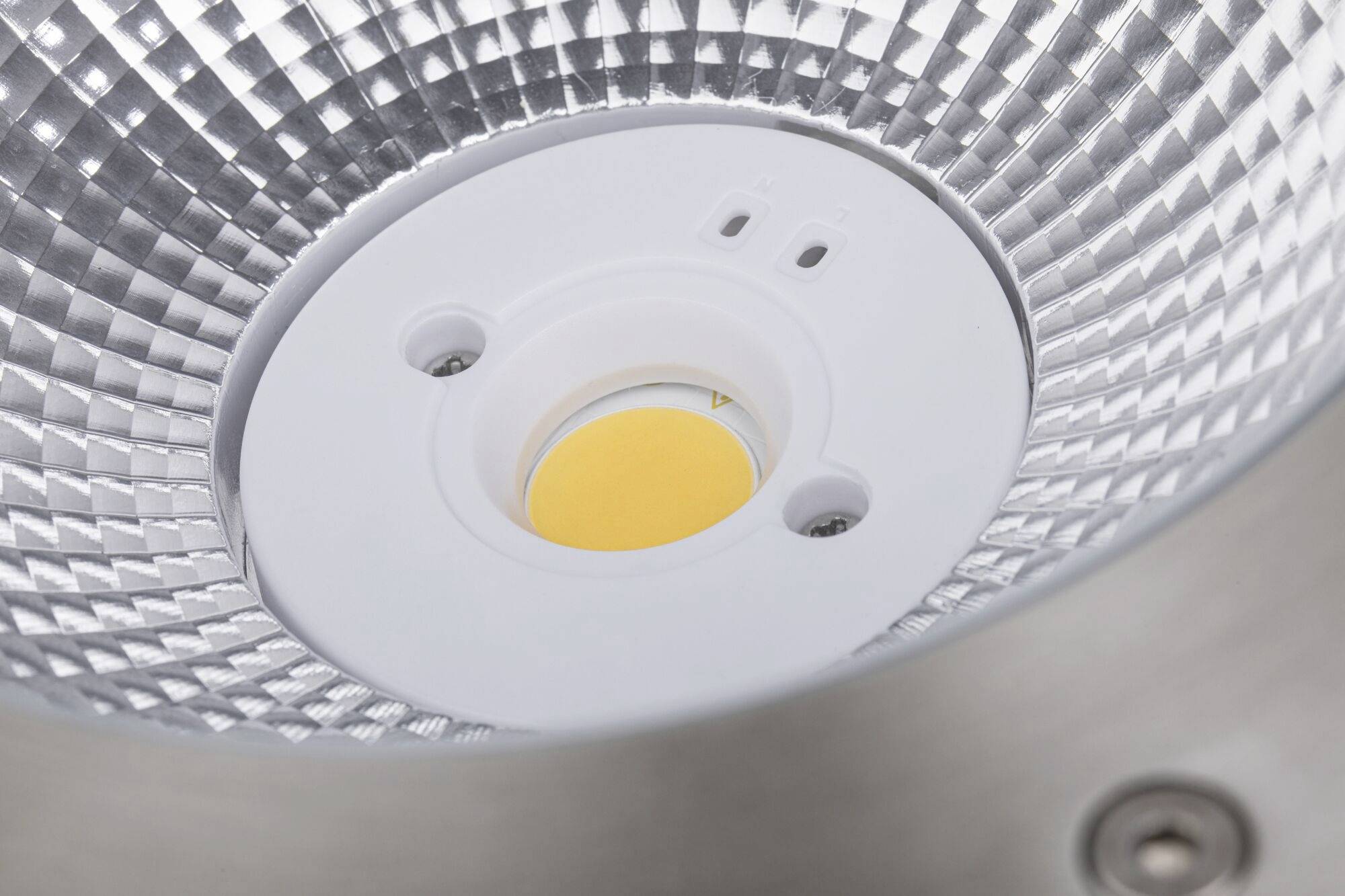 Nahaufnahme einer LED-Lampe in einer metallenen Fassung, die ein rasterförmiges Reflektordesign zeigt.